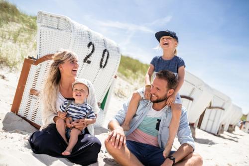 a family sitting in the sand on the beach at AKZENT Apartmenthotel Binz in Binz