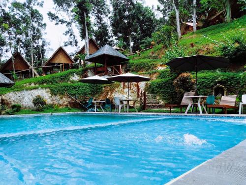 a swimming pool with umbrellas and tables and chairs at Victordelia Hilltop Hostel in San Vicente