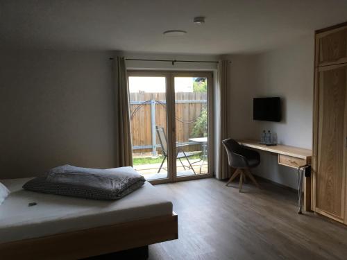 a bedroom with a bed and a desk and a window at Gaestehaus Richter in Oberammergau