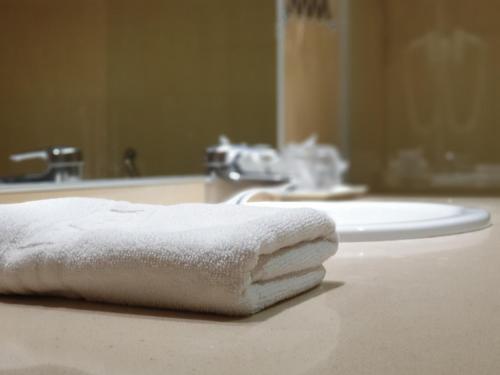 - une serviette blanche assise sur un comptoir de salle de bains en face d'un lavabo dans l'établissement Hotel Suite Camarena, à Teruel