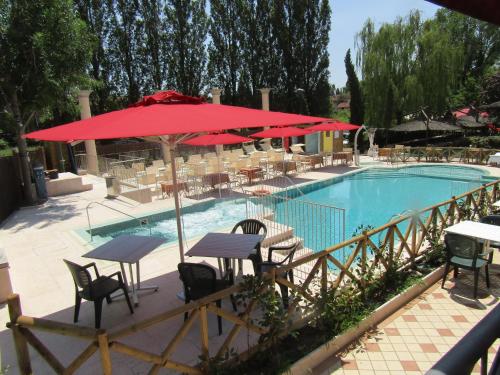 a pool with tables and chairs and a red umbrella at Sul Bacino in Massa Lombarda