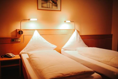 two beds in a hotel room with lights on the wall at Hotel & Restaurant Adler in Hornberg