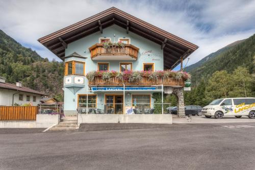 a building in a parking lot with cars parked at Café Landerl in Matrei in Osttirol