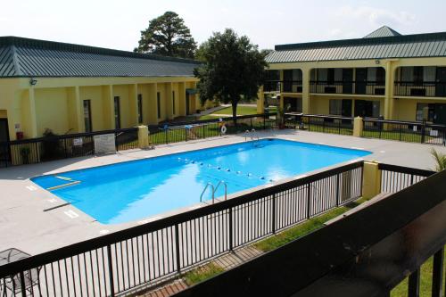 a large blue swimming pool in front of a building at Red Carpet Inn Kinston in Kinston
