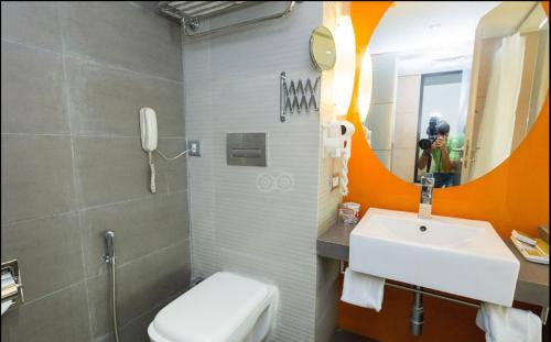 a bathroom with a sink and a toilet and a mirror at Meritas Picaddle Resort Lonavala in Lonavala