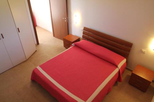 a bedroom with a red bed with a red blanket at Residence Le Casine in Batignano