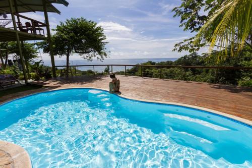 a person standing next to a blue swimming pool at Santa Teresa Surf Vista Villas in Santa Teresa Beach