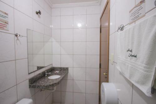 a white tiled bathroom with a sink and a mirror at Hotel Colonial in Baturité