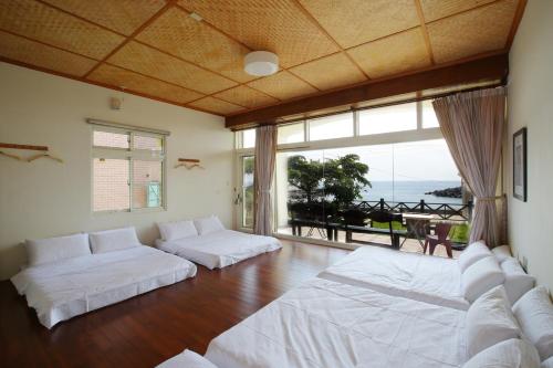 ein Wohnzimmer mit weißen Betten und einem großen Fenster in der Unterkunft Mama Tian Homestay in Xiaoliuqiu