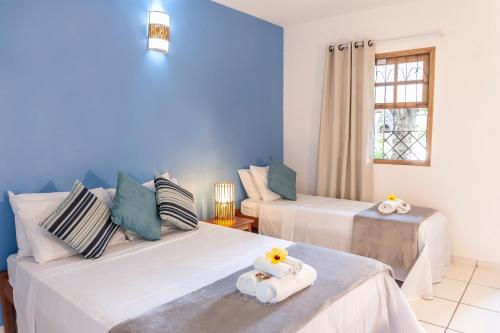 2 camas en una habitación con paredes azules en Pousada Flamboyant, en Arraial d'Ajuda