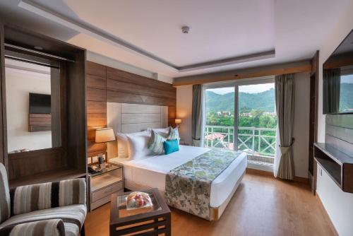 um quarto de hotel com uma cama e uma grande janela em Cygnett Resort Mountain Breeze em Nainital