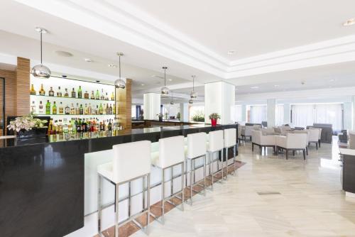 a restaurant with white chairs and a bar at Hotel Vista Park in Can Picafort