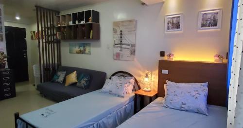 マニラにあるJen's Apartmentのベッド2台とソファが備わる小さな客室です。