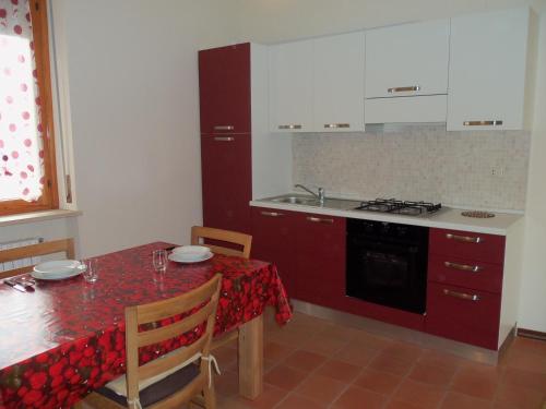 eine Küche mit einem Tisch und einem roten Tischtuch in der Unterkunft Appartamento San Bastian in CastellʼAlfero