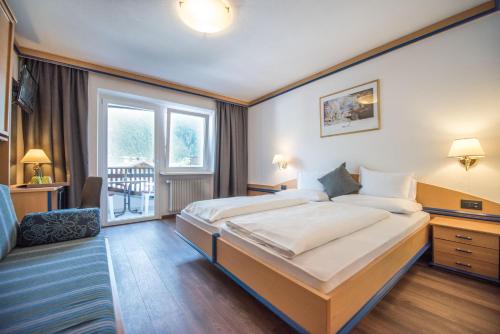 a hotel room with a large bed and a window at Vitaurina Royal Hotel in Molini di Tures