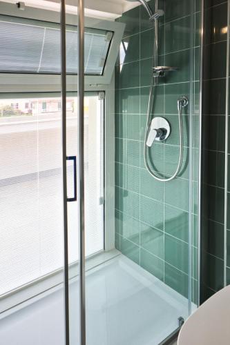 a bathroom with a shower with green tiles at Attico Mutti in Loano