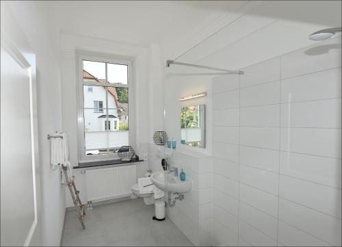 a white bathroom with a toilet and a sink at City Hotel ApartM3 am Park in Bad Oeynhausen