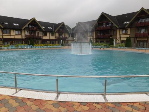 a large pool with a fountain in front of buildings at Wellness Hotel Bešeňová in Bešeňová