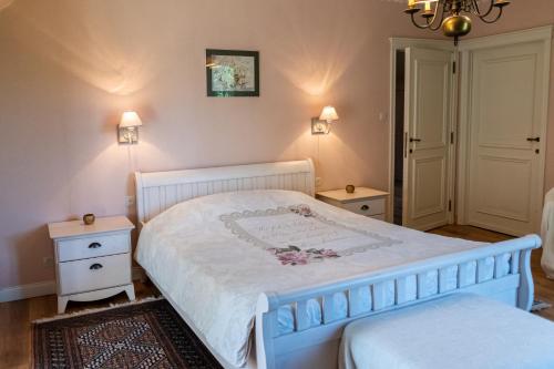 a bedroom with a white bed and two night stands at B&B El Tyu in Écaussinnes-dʼEnghien