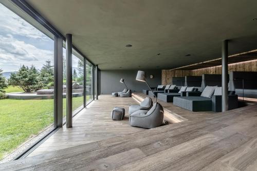 a living room with couches and chairs on a deck at Sporthotel Sonne in Alpe di Siusi