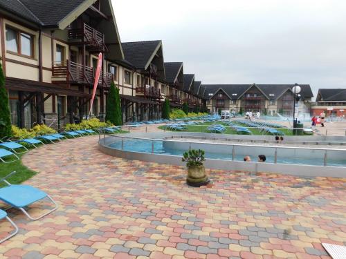 a courtyard with a pool and some chairs and buildings at Wellness Hotel Bešeňová in Bešeňová