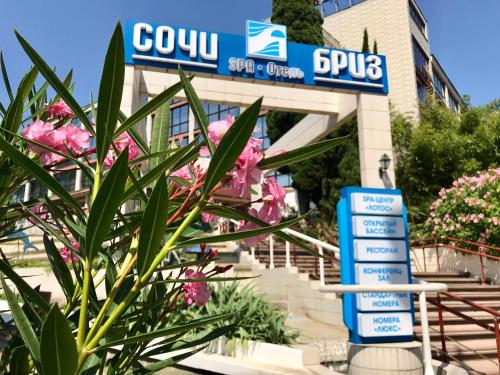 a sign in front of a building with pink flowers at Sochi-Breeze Spa Hotel in Sochi