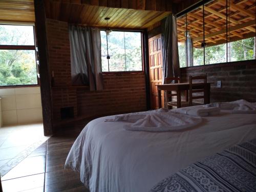 ein Schlafzimmer mit einem Bett in einem Zimmer mit Fenstern in der Unterkunft Pousada Pizzaria do Vale in Visconde De Maua