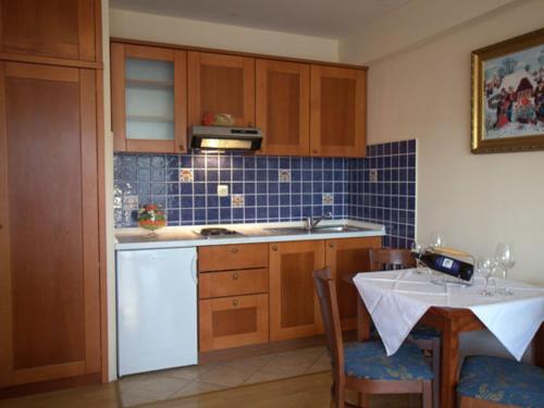 a kitchen with wooden cabinets and a table and a white dishwasher at Studio Apartmani Bijeli Delfin in Biograd na Moru