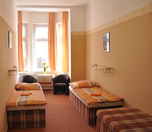 a hotel room with three beds and a window at Hostel Děčín in Děčín