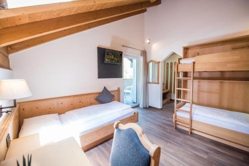 a bedroom with two beds and a desk and a chair at Vitaurina Royal Hotel in Molini di Tures