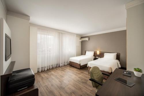 um quarto de hotel com duas camas e uma secretária em Intercity São Paulo Nações Unidas em São Paulo