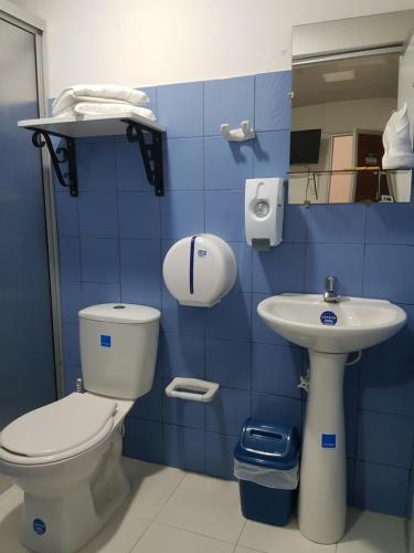 a blue tiled bathroom with a toilet and a sink at Hotel La Posada in Belén de Umbría