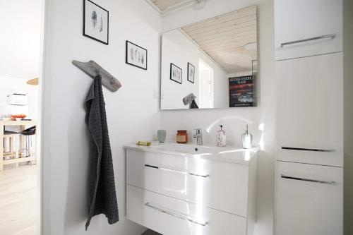 La salle de bains est pourvue d'un lavabo blanc et d'un miroir. dans l'établissement Romantic Klaksvik apartment, à Klaksvík