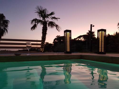 a swimming pool with a palm tree and a wine glass at Folco Studio Apartment in Piazza Armerina