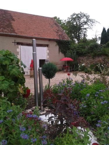 un jardin avec un parasol rouge en face d'une maison dans l'établissement Le Clos de la Fontaine, à Massay