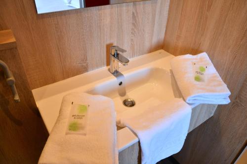 a bathroom with a sink with two towels on it at The Originals Access Aéroport, Hôtel Aurillac in Aurillac