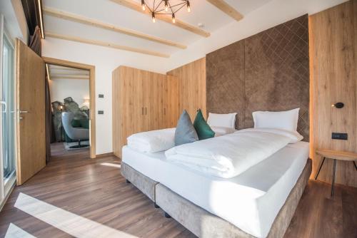 a bedroom with a large white bed with blue pillows at Vitaurina Royal Hotel in Molini di Tures