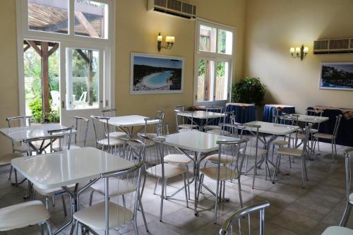 a restaurant with white tables and chairs and windows at Solanas Termas de Dayman in Termas del Daymán