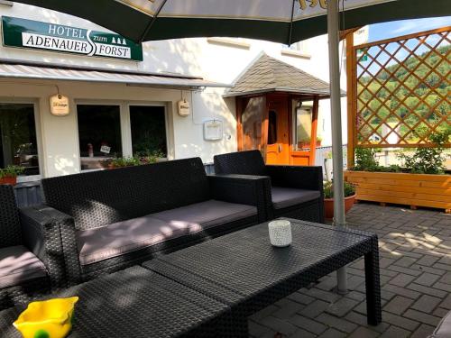 a patio with a couch and a table and an umbrella at Hotel garni Zum Adenauer Forst in Wimbach