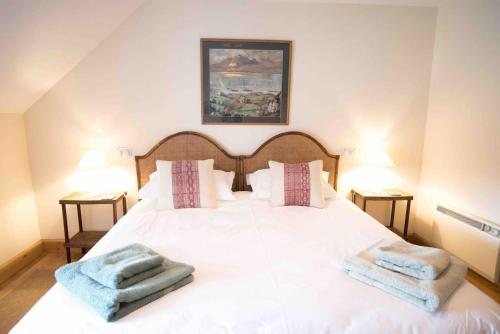 a bedroom with a white bed with two towels on it at Coachmans Bothy - 50m from the beach in Port Appin