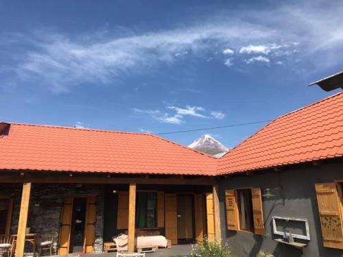 an orange roofed building with a mountain in the background at Sno House in Kazbeg in Sno