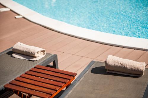 two towels sitting on a bench next to a swimming pool at Giardini Mon Plaisir in Trapani