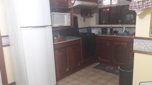 - une cuisine avec des placards en bois et un réfrigérateur blanc dans l'établissement apto centro de gramado, à Gramado
