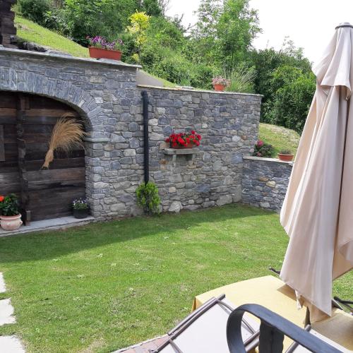 a garden with a stone wall and an umbrella at Maison Venoir1 in Aymavilles