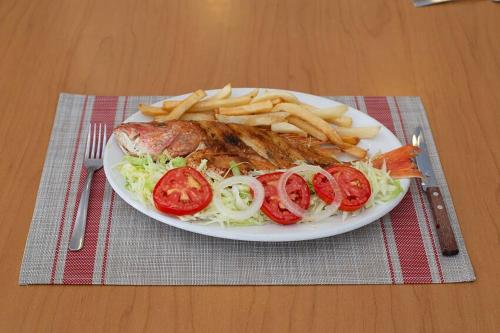 a plate of food with fries and a plate of fish and vegetables at Hotel Plaza Palmas in Tuxpan de Rodríguez Cano