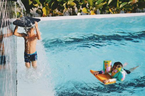 two children playing in the water at a swimming pool at Wannachart Boutique Resort in Tha Sala