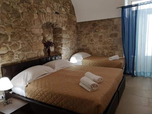 - 2 lits dans une chambre avec un mur en pierre dans l'établissement La Corte Di Ibla, à Raguse