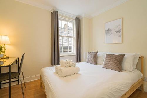 a bedroom with a white bed with a desk and a window at 2BR Grassmarket Apartment with Castle View in Edinburgh