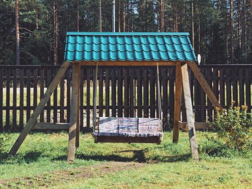 a wooden swing set with a blue roof at Guesthouse Husky Moa in Poselok-Matrosy