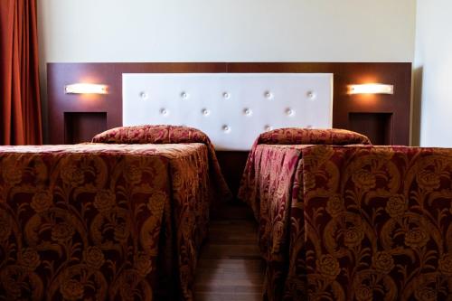 two beds in a room with red curtains at Hotel Villa Venus Resort & SPA in Atena Lucana